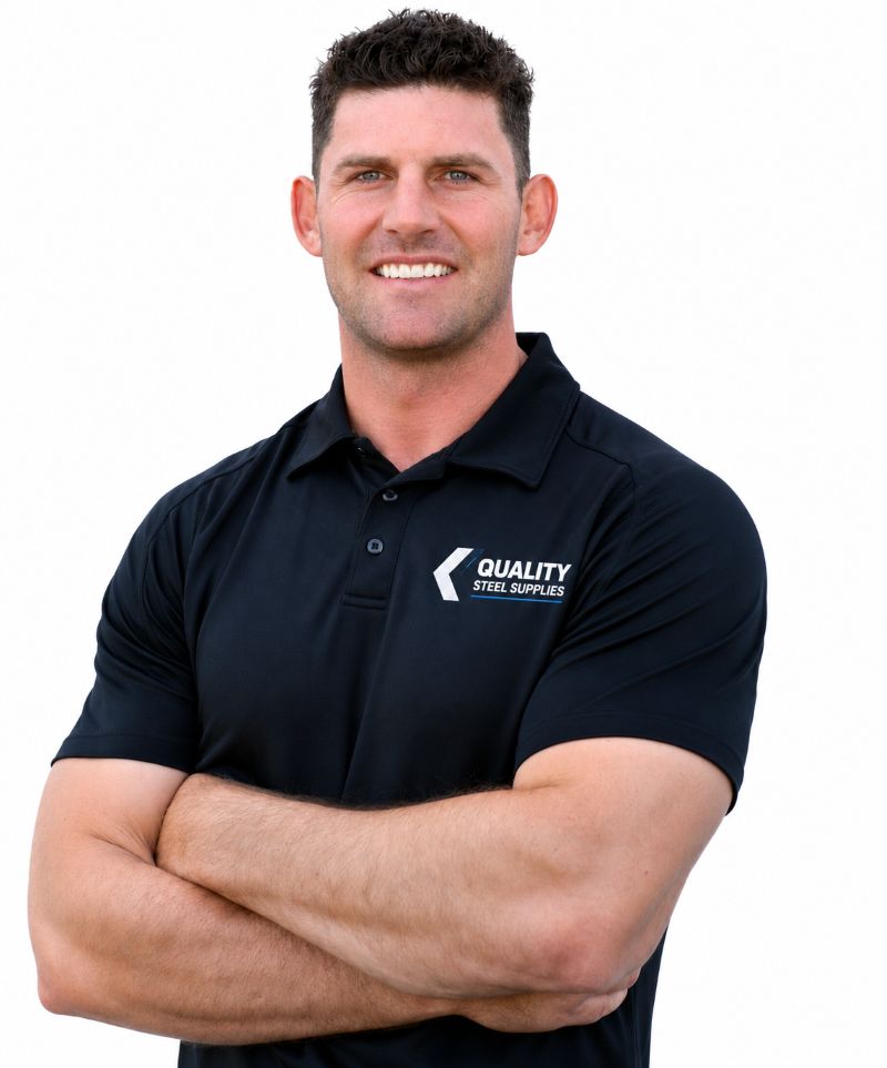 Smiling man in a black polo with arms crossed, wearing the Quality Steel Supplies logo on his chest.